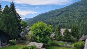 Uma aldeia rural com casas de madeira tradicionais, rodeada por vegetação exuberante e montanhas.