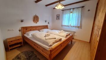 Ein hölzernes Bett mit Kopfteil, ein Nachttisch, ein flauschiger Teppich und ein Fenster mit Vorhängen.