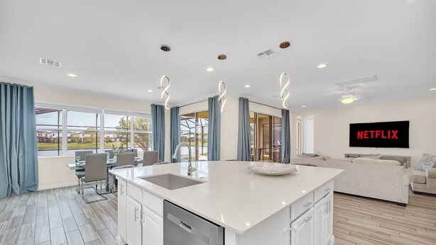 A modern kitchen with a central island, a dining area with a table and chairs, a living room with a sofa, and a large window with curtains. - LAKE VILLA 6bd/all un-suite, pool*spa*grill (Kissimmee)