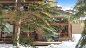 A two-story building with a snow-covered ground, large windows, and outdoor seating. - East Vail Townhome - Close to Racquet Club (Vail)