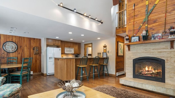 A spacious living area with a fireplace, wooden accents, and a kitchen with modern appliances. - East Vail Townhome - Close to Racquet Club (Vail)