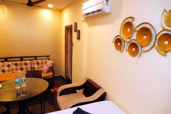 Habitación de hotel con sofá, una mesa redonda, una silla y un adorno en la pared.