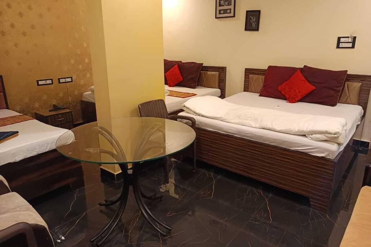 A hotel room with two single beds, a glass table, and a wooden headboard.
