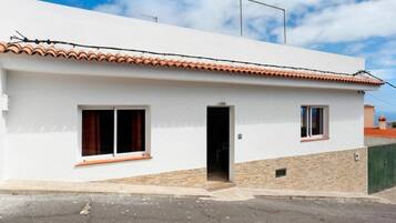 A white building with a tiled roof, two windows, and a door.