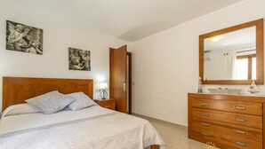 A bedroom with a wooden bed, a nightstand, a dresser, and a large mirror. - House in Pollensa near Cala Barqués Beach (Pollensa)