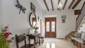A spacious living area with a wooden staircase, a sofa, a dining table with chairs, and a large mirror. - House in Pollensa near Cala Barqués Beach (Pollensa)