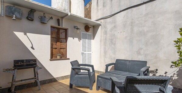 Une petite terrasse avec des meubles en osier, une porte en bois et une petite table.