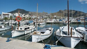 A marina with boats docked, a lifebuoy, and buildings in the background. - House in Pollensa near Cala Barqués Beach (Pollensa)