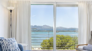 A room with a view of a marina, a balcony with a railing, and a sofa with patterned cushions.