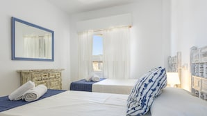 A hotel room with two beds, a large mirror, a dresser, and a window with curtains.