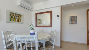 A dining area with a round table and four chairs, a vase with flowers, and artwork on the walls.