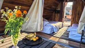 A cozy, wooden cabin with a bed, a table with fruit and flowers, and an air conditioning unit. - Mango Villa Nong Khiaw (Nong Khiaw)