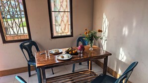 A dining area with a wooden table, blue chairs, and a vase with flowers. - Mango Villa Nong Khiaw (Nong Khiaw)