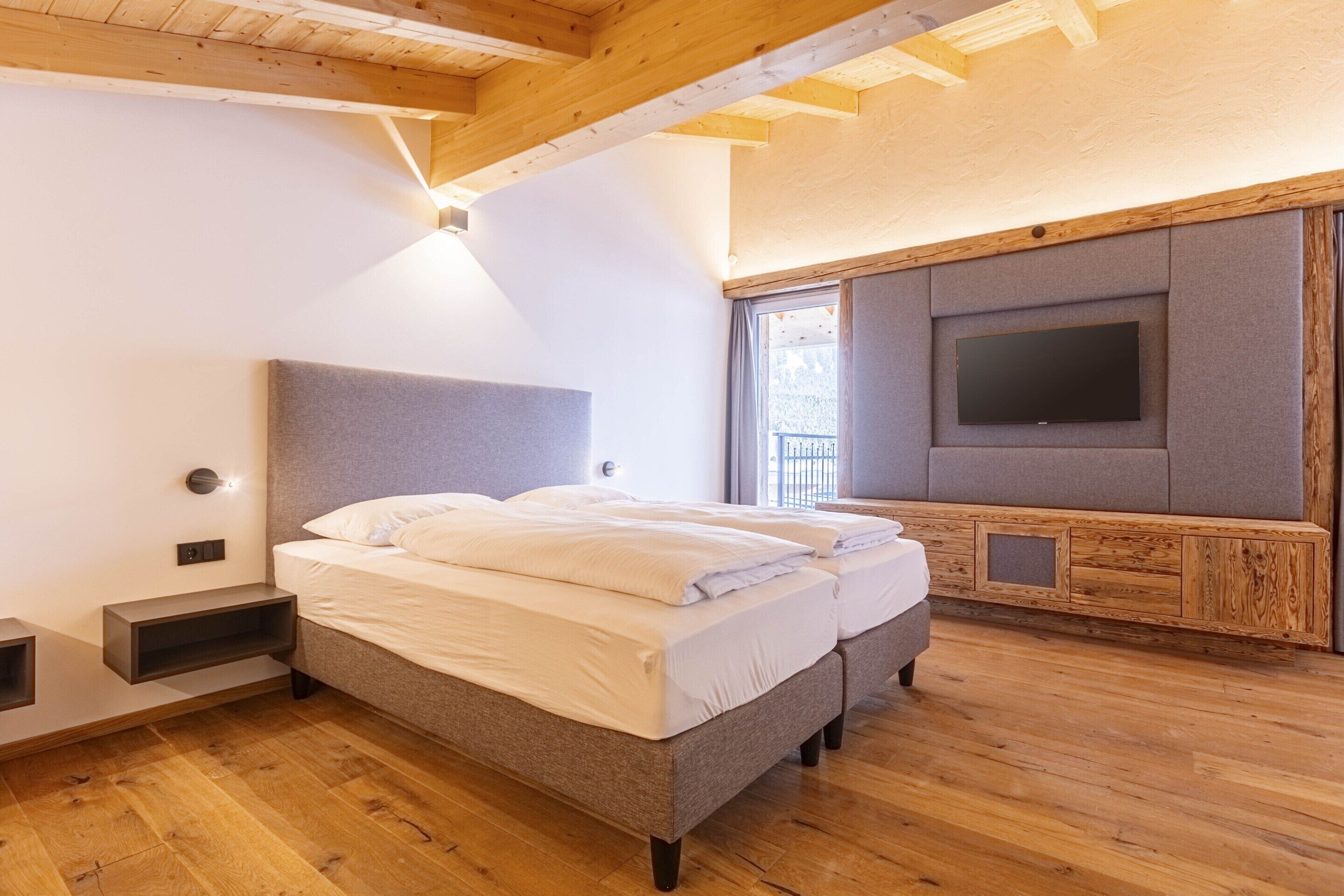 Ein Schlafzimmer mit Bett, Fernseher und Holzboden.