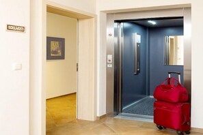 Um elevador com uma mala vermelha e uma placa com a inscrição 'ELEVADOR'.