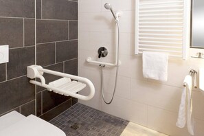 Um banheiro moderno com chuveiro, um porta-toalhas branco e vaso sanitário.