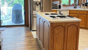 Une cuisine dotée de meubles en bois, d’un réfrigérateur en acier inoxydable, d’une cuisinière encastrée et d’un grand îlot central.