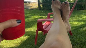 Une personne se détend sur une chaise rouge au bord d’un lac, avec des bateaux en arrière-plan.