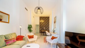 Una sala de estar moderna con un sofá, dos sillones, una mesa de centro, un televisor y un comedor con una mesa y sillas.