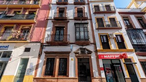 Un edificio de varios pisos con balcones, un letrero de consultorio médico y una tienda Mapfre.