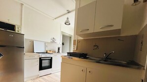 A modern kitchen with white cabinetry, a stainless steel refrigerator, a built-in oven, and a sink. - On grassland (Malmerspach)