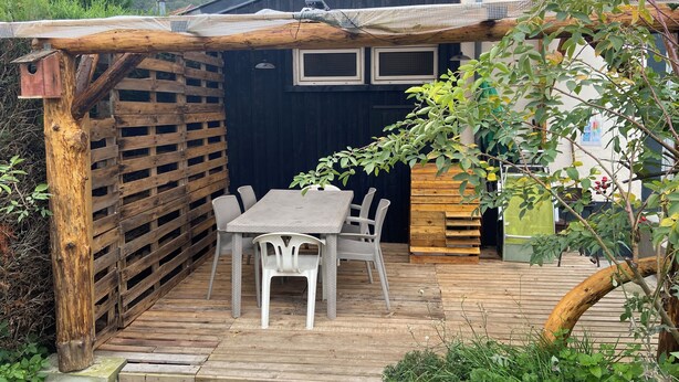 A wooden deck with a table and chairs, surrounded by a wooden fence and a pergola. - On grassland (Malmerspach)
