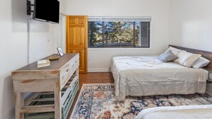 Una camera da letto con un letto, una scrivania, una televisione, una finestra e una porta.
