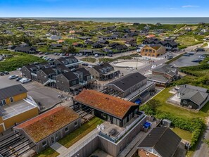 A coastal residential area with modern houses, a central roundabout, and a view of the sea.