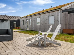 Un edificio moderno con rivestimento in legno, un tetto verde e una terrazza con mobili da esterno.