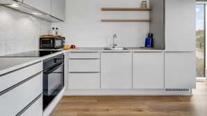 Eine moderne Küche mit Mikrowelle, Backofen und Holzregalen.