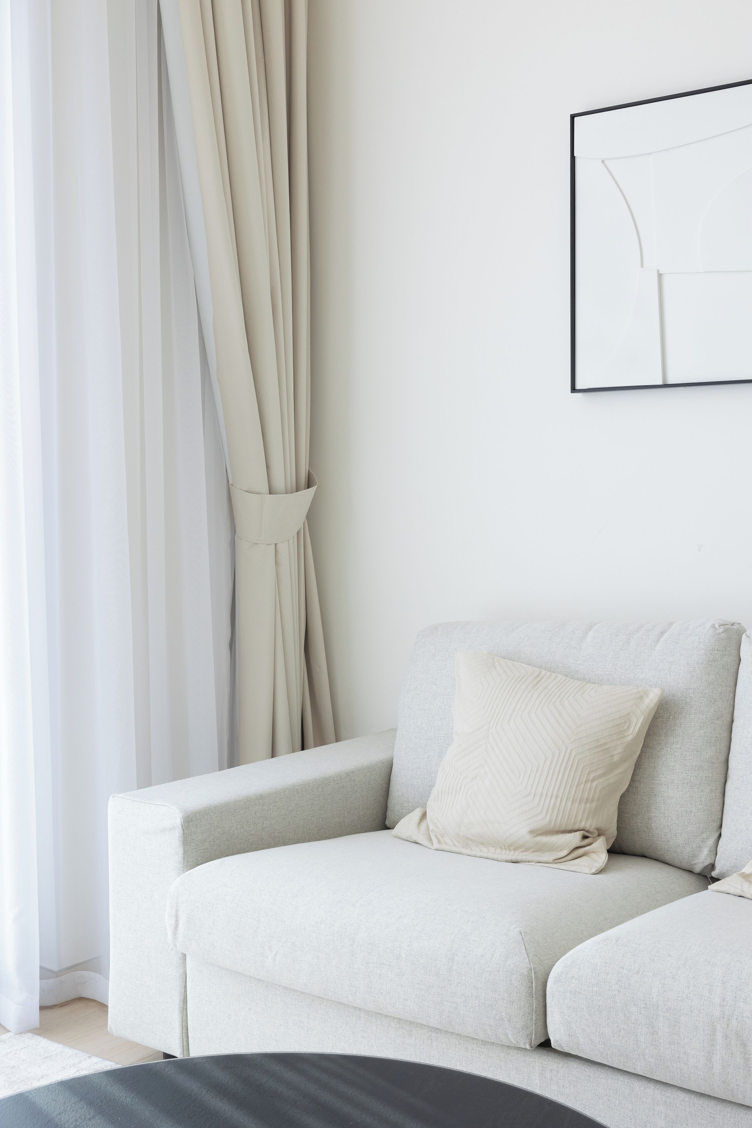 A minimalist living room with a light-colored sofa, a white pillow, and a framed picture on the wall.