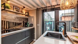 Una cucina moderna con piano di lavoro bianco, lavello nero e lampadario a sospensione.