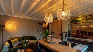 Una cucina moderna con isola in legno, luci a sospensione e pannelli posteriori in pietra.