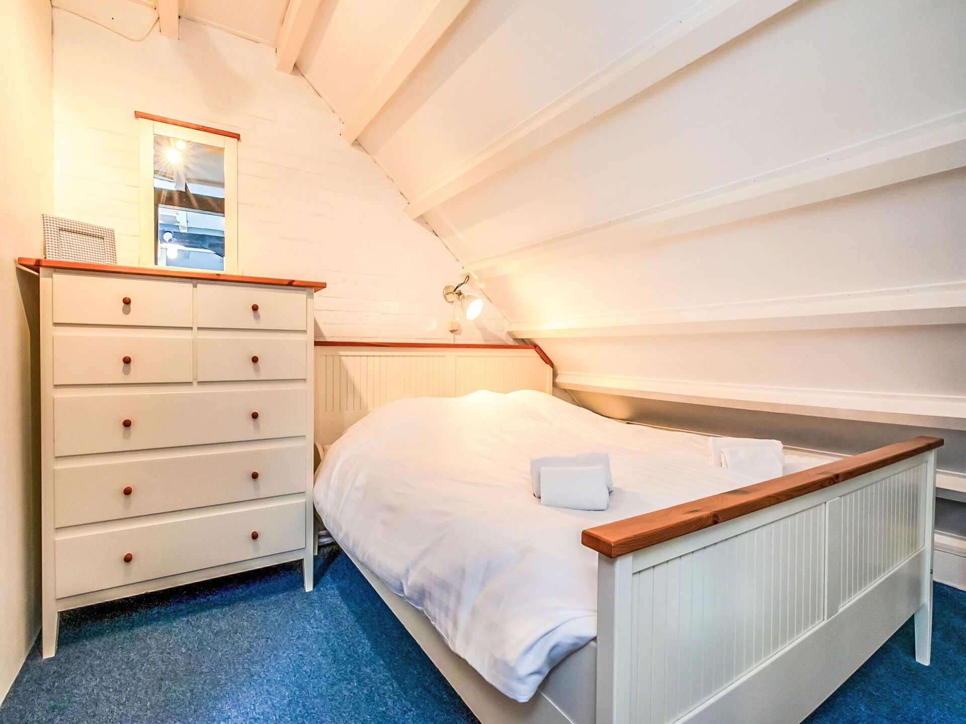 Une chambre avec un lit simple, une commode à tiroirs, un miroir et une fenêtre.