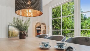 Una zona de comedor con una mesa de madera, dos tazas azul y blanco, un cuenco de aceitunas y una revista sobre la mesa.