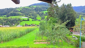 Paisagem rural com campos verdes, uma pequena aldeia e uma estrada com ciclovia.