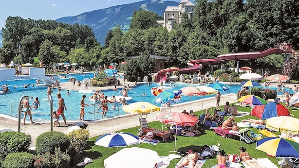 Um resort com várias piscinas, um tobogã e espreguiçadeiras.