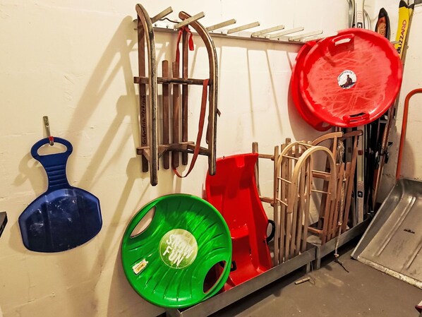 A rack with various metal tools and equipment, including a blue and a green tool with a handle, and a red tool with a circular handle.