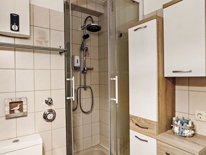 A modern bathroom with a glass-enclosed shower, a toilet, and a vanity with a wooden countertop. - Nice apartment for 5 people with WIFI, TV and balcony (Winterberg)