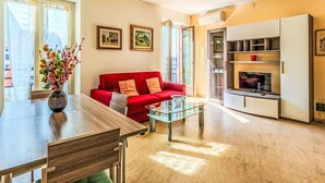 A modern living room with a red sofa, glass coffee table, and a TV on a wooden cabinet. - Lovely apartment for 3 guests with A/C, WIFI, TV, patio, pets allowed and panoramic view (Malcesine)