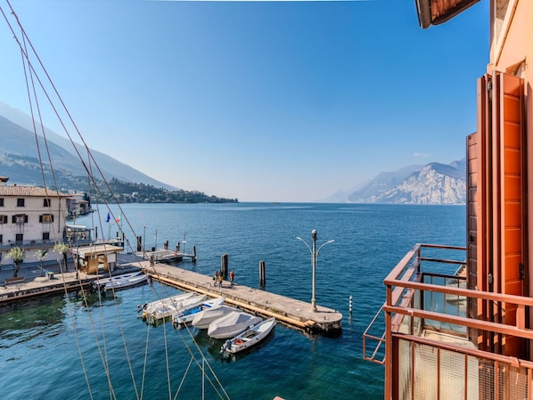 A marina with boats docked, a pier extending into the water, and a building with a balcony overlooking the scene.