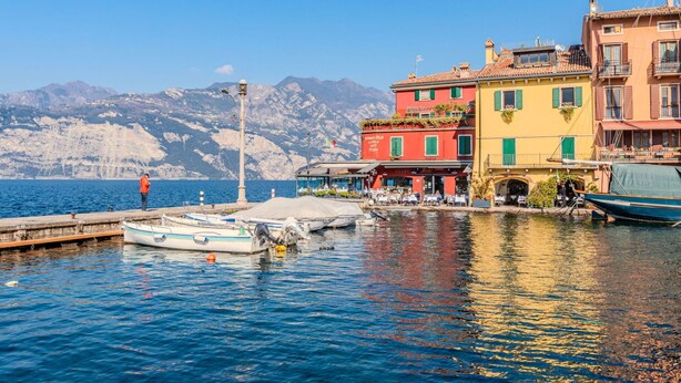 A waterfront scene with colorful buildings, a dock with boats, and a mountainous backdrop. - Lovely apartment for 3 guests with A/C, WIFI, TV, patio, pets allowed and panoramic view (Malcesine)