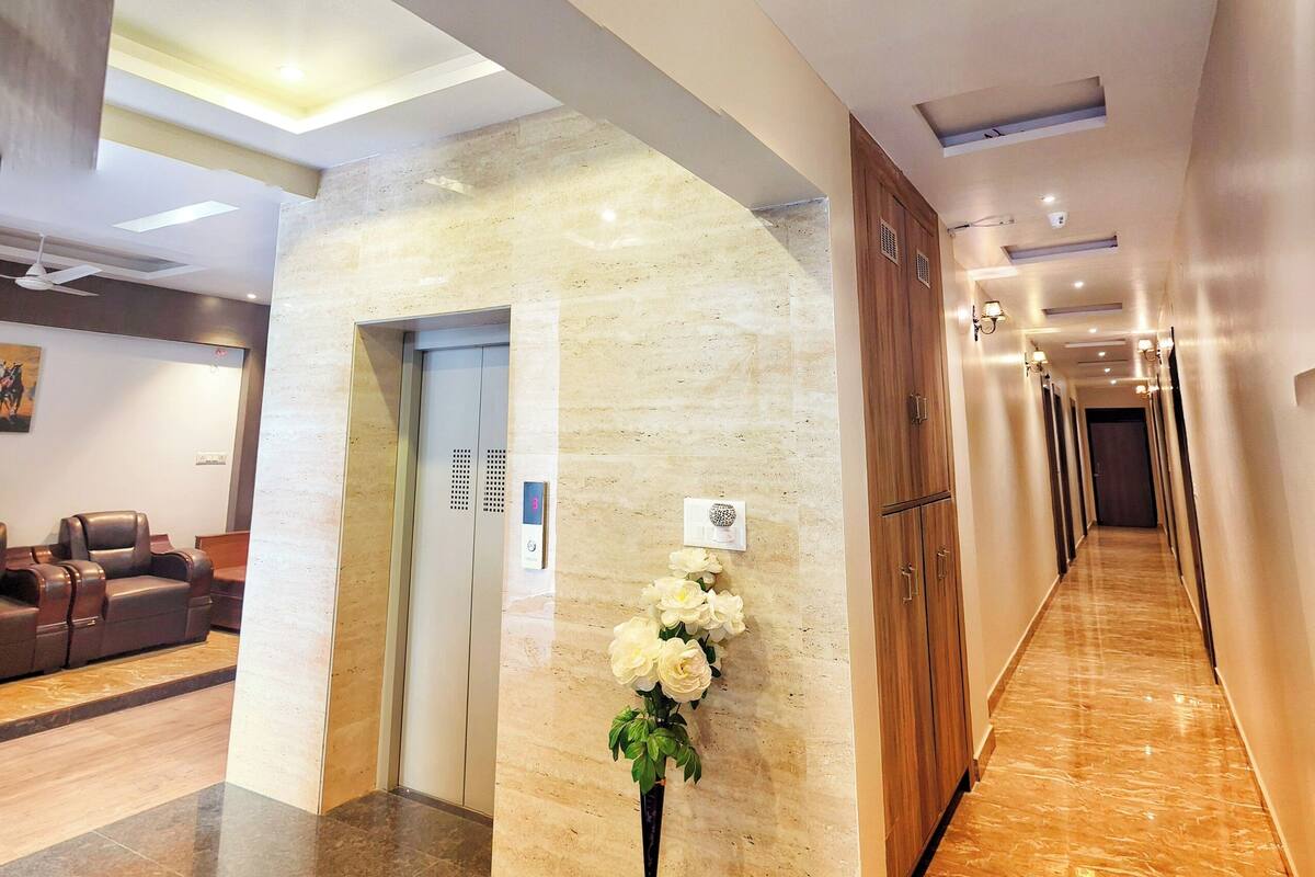 Eine Hotelhalle mit Marmorboden, einer Rezeption, einem Aufzug und einem Korridor mit Wandleuchten.