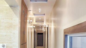 Un couloir doté d’un sol en marbre, de meubles en bois et de luminaires fixés au mur.