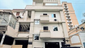 Un immeuble à plusieurs étages avec une entrée de garage, un VUS garé et une enseigne bien visible indiquant « Elegance Suites ».