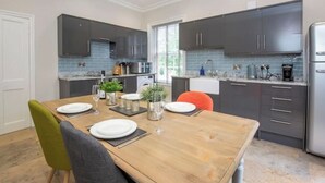 Una cucina moderna con mobili scuri, un tavolo da pranzo in legno apparecchiato per quattro persone e una finestra che fa entrare luce naturale.