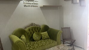 En grøn sofa med mønstrede puder, et marmorbord og et vægur.