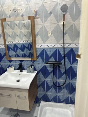 A bathroom with a sink, mirror, shower, and toilet.
