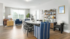 Una sala moderna con una mesa de comedor, sillas a rayas azules, un sofá y una estantería.