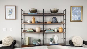 Un comedor con una mesa de mármol, una silla negra, una estantería de madera con objetos decorativos y una obra de arte enmarcada en la pared.
